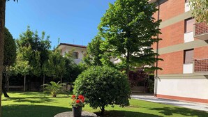 A courtyard with a stone table, potted plants, and a brick building in the background. - Holiday apartment with air conditioning (Massa)