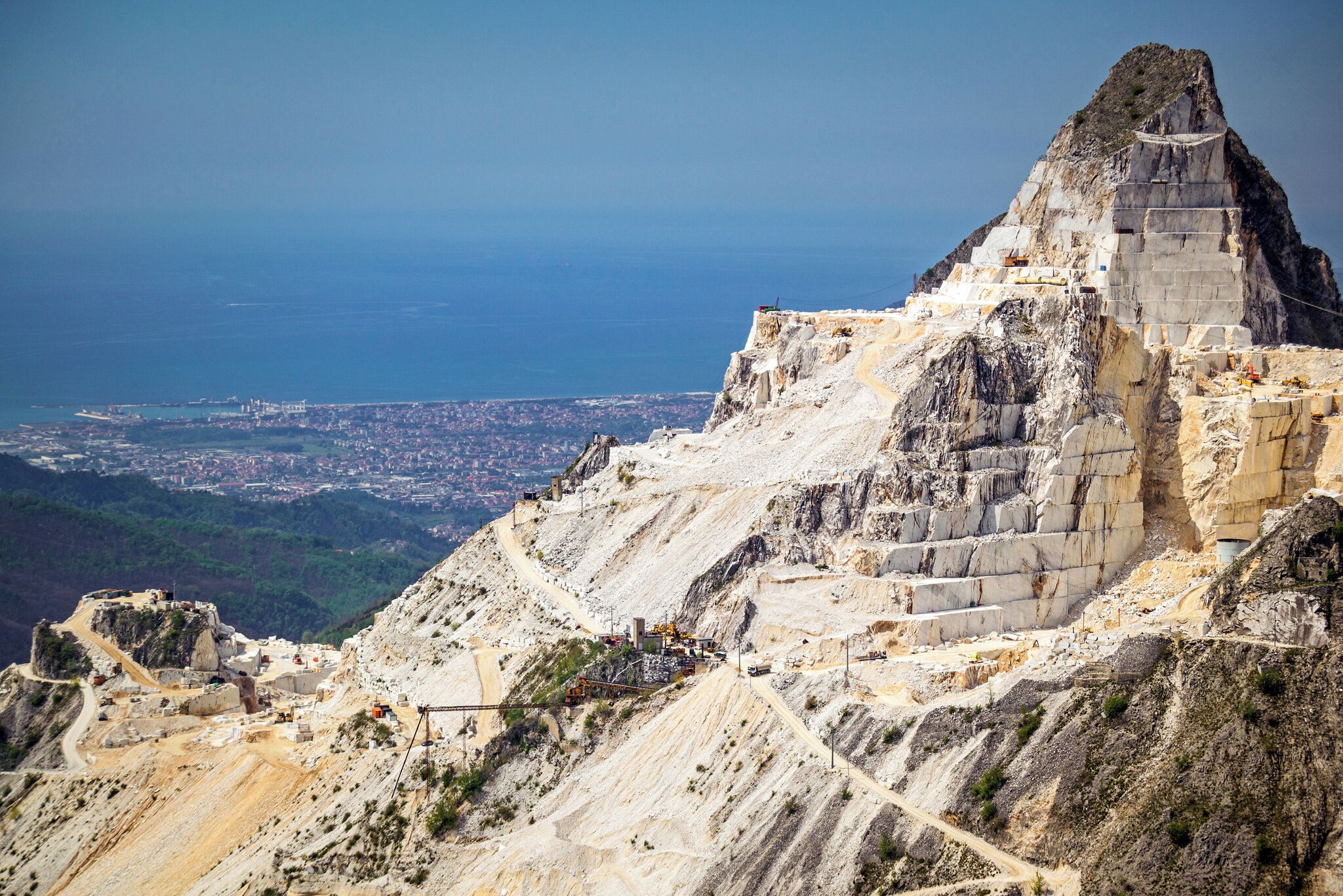 Eine gebirgige Landschaft mit einem markanten Felsen und Blick auf eine ferne Stadt.