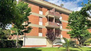 A multi-story building with a brick facade, balconies, and a well-maintained lawn with trees. - Holiday apartment with air conditioning (Massa)