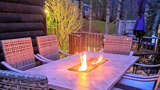 Eine Holzterrasse im Freien mit einem rechteckigen Tisch und sechs Korbstühlen.