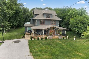 A two-story house with a front porch, a basketball hoop, and a well-maintained lawn.