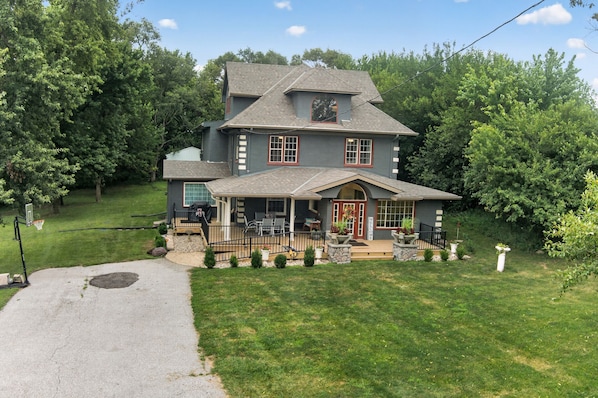 A two-story house with a front porch, a basketball hoop, and a well-maintained lawn.