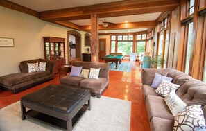 A spacious living room with a pool table, two sofas, and a coffee table.