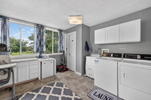 A laundry room with a washing machine, dryer, and ironing station.