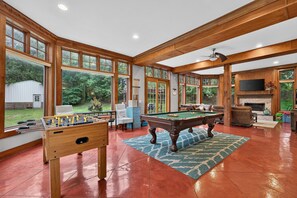 A spacious indoor area with a pool table, a foosball table, and a fireplace.