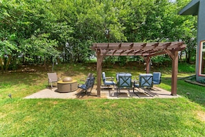 A covered patio area with outdoor furniture, a fire pit, and a pergola structure.