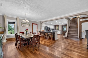 A spacious kitchen with a dining area, wooden flooring, and a view of the outdoors.