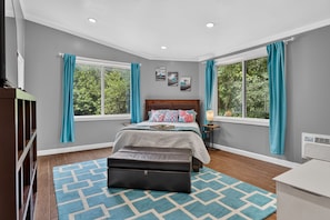A bedroom with a bed, a nightstand, a dresser, and a window with curtains.