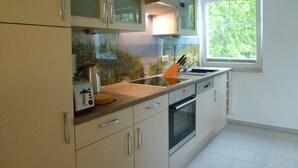 A modern kitchen with a built-in oven, a coffee maker, and a window providing natural light. - Beautiful apartment on the 1st floor! - Hafenstrasse 15 in Prerow (Prerow)