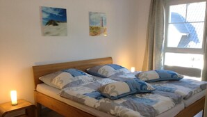 A bed with a wooden frame, two bedside tables, and two wall-mounted paintings. - Beautiful apartment on the 1st floor! - Hafenstrasse 15 in Prerow (Prerow)