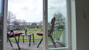 A room with a large window overlooking a patio area with outdoor furniture and a view of a park. - Beautiful apartment on the 1st floor! - Hafenstrasse 15 in Prerow (Prerow)