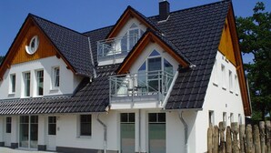 A two-story house with a sloped roof, large windows, and a balcony. - Beautiful apartment on the 1st floor! - Hafenstrasse 15 in Prerow (Prerow)
