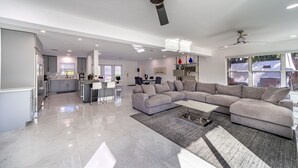 En rummelig opholdsstue med en stor grå modulsofa, et sofabord og en loftventilator.