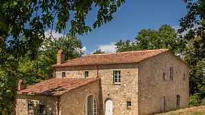 A stone building with a tiled roof, arched windows, and a small porch.