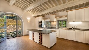 A modern kitchen with white cabinetry, a central island, and a stone wall view.