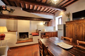 Eine rustikale Küche mit Holzbalken, einer Fliesenrückwand und einem Essbereich mit Holztisch und Stühlen.