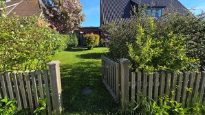 A residential property with a paved driveway, a wooden fence, and a variety of greenery. - Hook - Holiday apartment Hook - with south-facing terrace, very quiet location (Midlum)