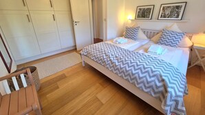 A bedroom with a bed, a wardrobe, a bedside table, and two framed pictures on the wall. - Hook - Holiday apartment Hook - with south-facing terrace, very quiet location (Midlum)