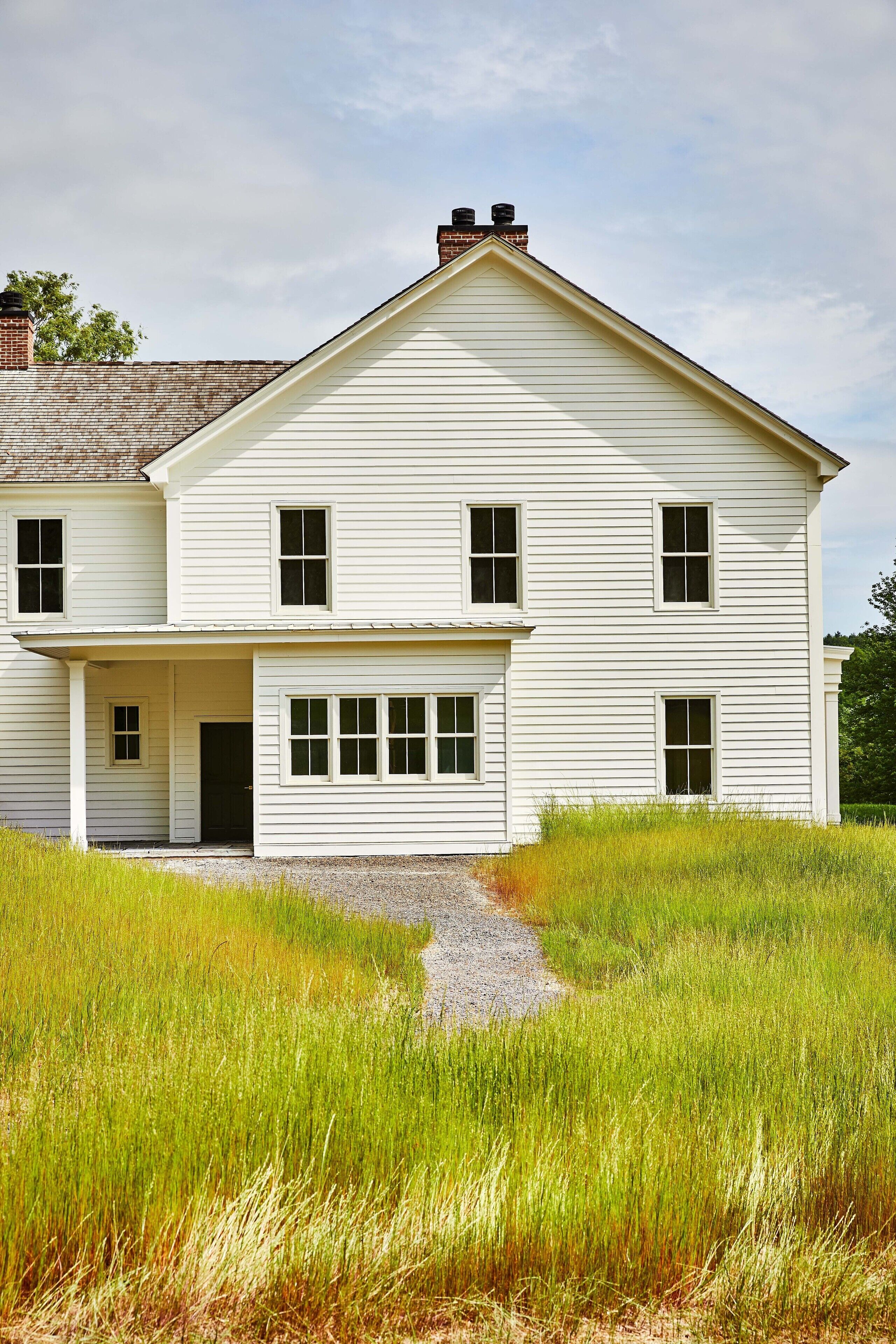 A two-story white house with a front porch and a chimney.