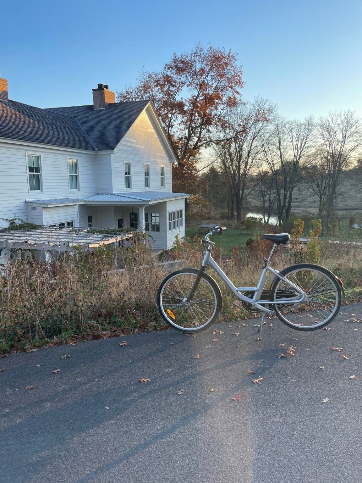 A bicycle parked on a paved road with a white house in the background.