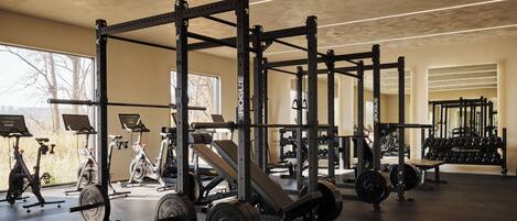 Un gimnasio con equipo de levantamiento de pesas, bicicletas estáticas y discos de pesas.