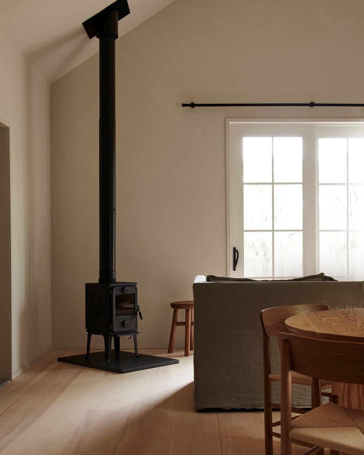 A living room with a black wood-burning stove, a wooden dining table, and a sofa.