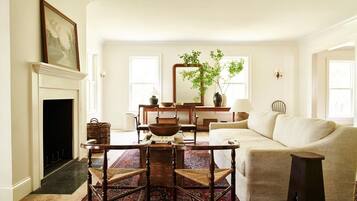 A living room with a fireplace, a sofa, a dining table with chairs, and a large mirror.