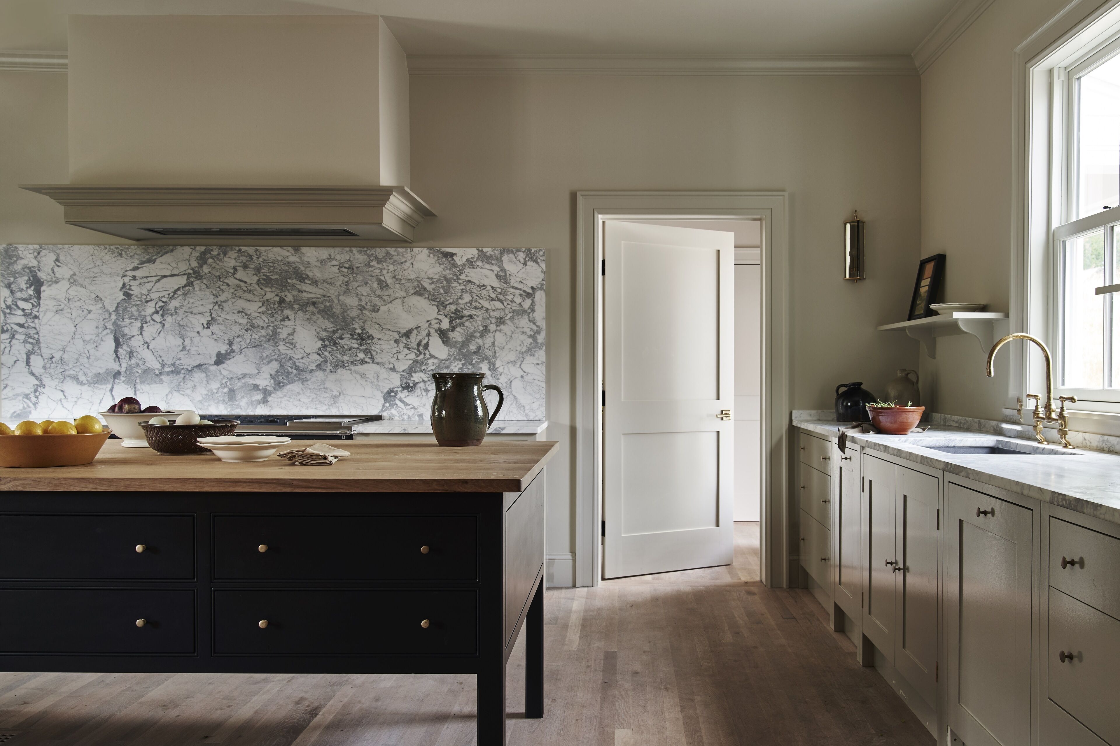Una cocina con salpicadero de mármol, encimera de madera y muebles oscuros.