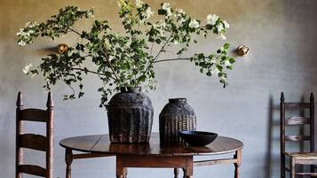 A round wooden table with two chairs, a vase with flowers, and a bowl.