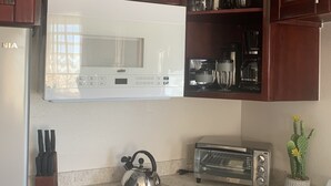 Una cocina equipada con estufa a gas, microondas, tostadora y hervidor.