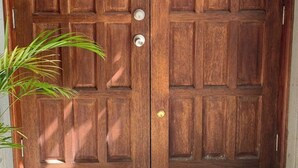 Una puerta doble de madera con un panel de vidrio y un timbre.