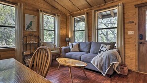A cozy cabin interior with wooden walls, a sofa, a table, and a chair.