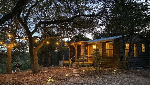 A rustic cabin with a wooden exterior, a porch, and string lights.
