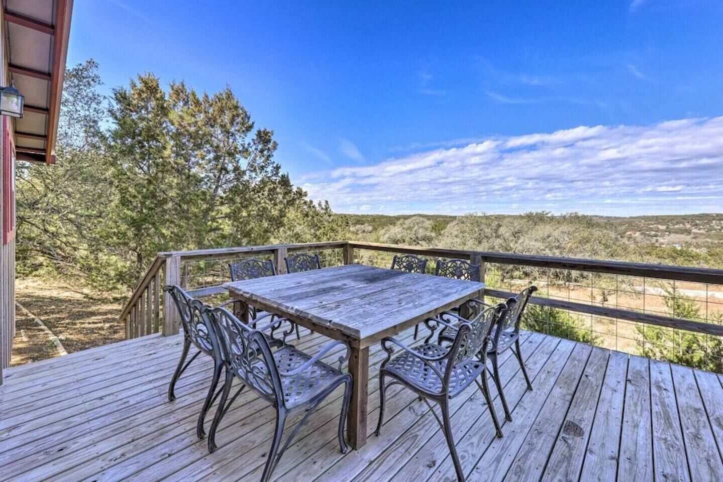 Een houten terras met een tafel en stoelen, met uitzicht op een natuurlandschap.