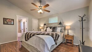 A bedroom with a bed, a ceiling fan, a nightstand, and a coat rack. - Las Estrellas Lots of privacy with stunning views, 2 decks, private hot tub! (Wimberley)