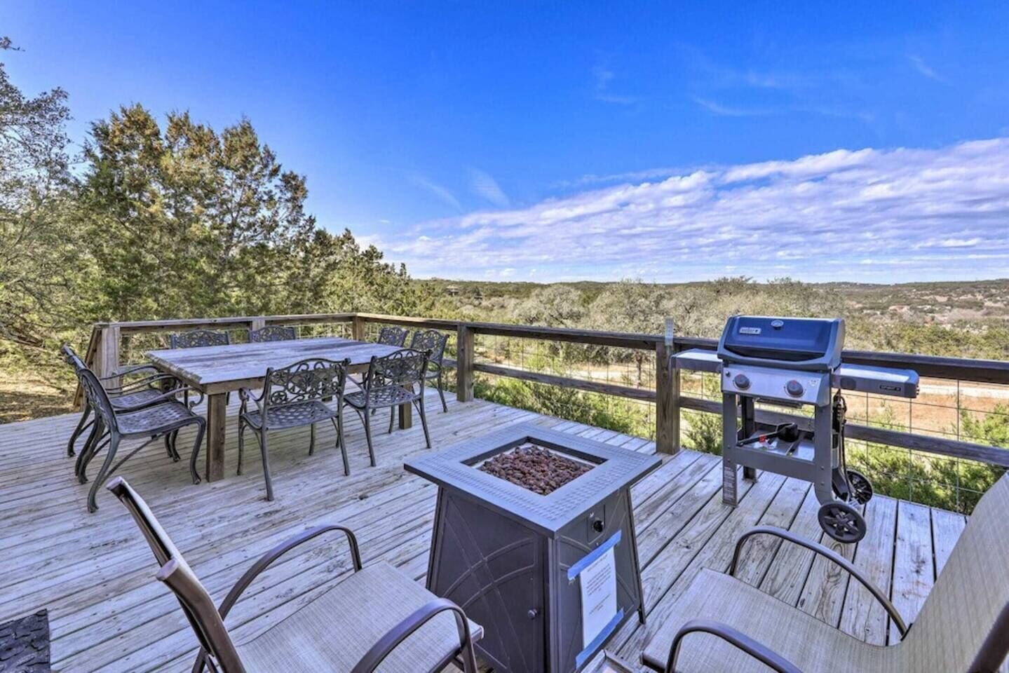 Una terraza de madera con una mesa, sillas, una parrilla y una chimenea.
