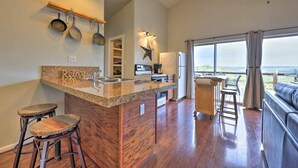 A modern kitchen with granite countertops, a built-in stove, and a large island with stools. - Las Estrellas Lots of privacy with stunning views, 2 decks, private hot tub! (Wimberley)