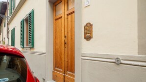 Un bâtiment avec une porte en bois, une plaque de numéro et une voiture garée devant.