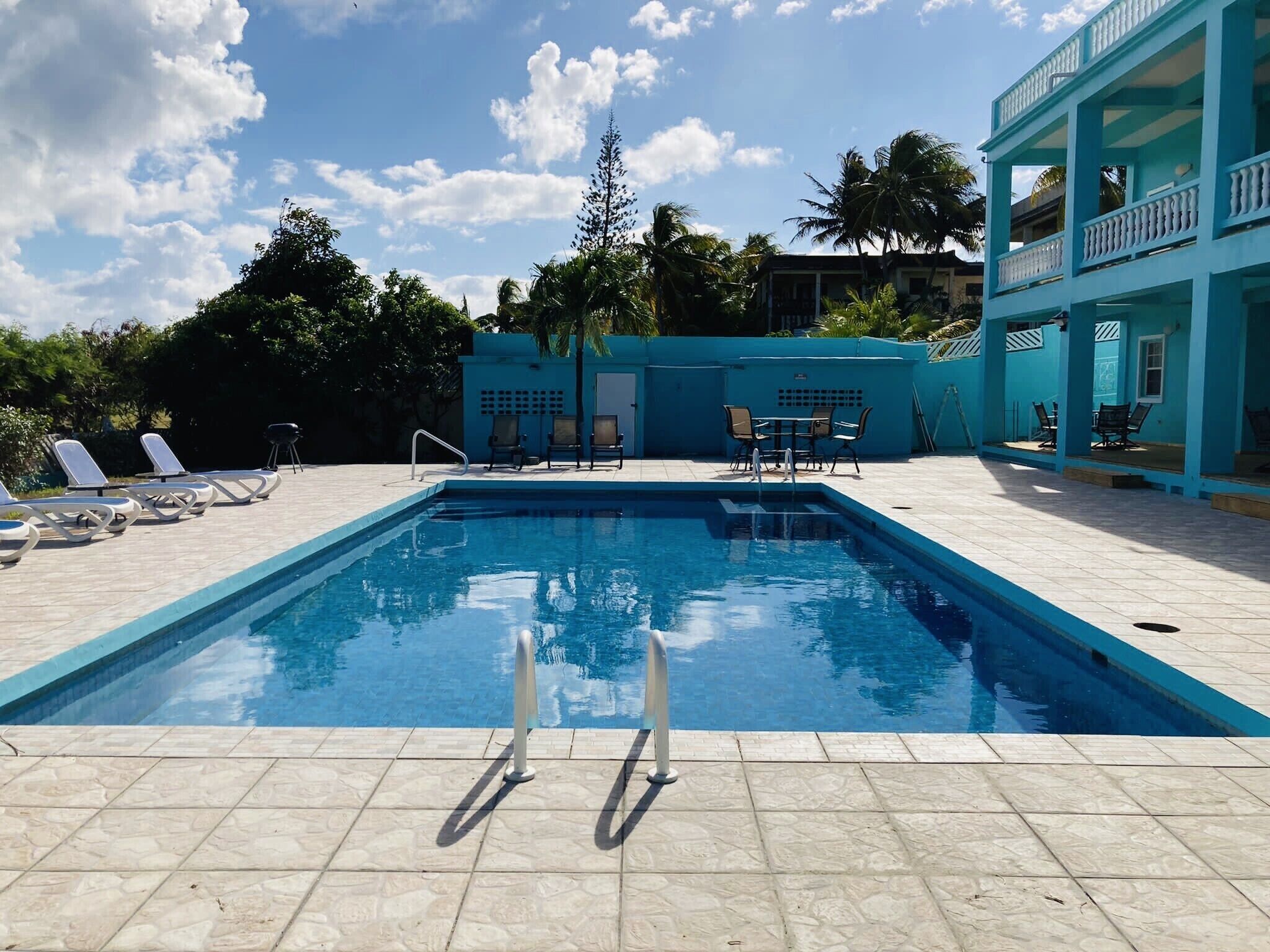 Una piscina con sillas de descanso y una zona de estar techada.