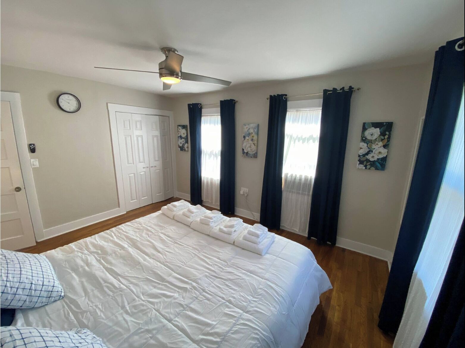 Ein Schlafzimmer mit Bett, Deckenventilator, einer Uhr und einer Tür.