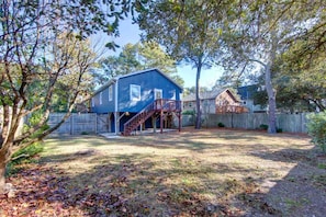 A two-story blue house with a wooden deck and a staircase leading to the second floor. - Tucker’s Treehouse - pup friendly with fully fenced yard & hot-tub! (Kill Devil Hills)