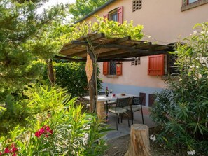 Une agréable terrasse extérieure agrémentée d’une pergola en bois, d’une table ronde et de chaises.