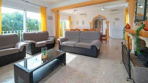 A spacious living area with a sofa set, a glass coffee table, and a dining area in the background. - Stunning private villa for 17 people with WIFI, private pool, A/C, TV, patio and pets allowed (Calpe)