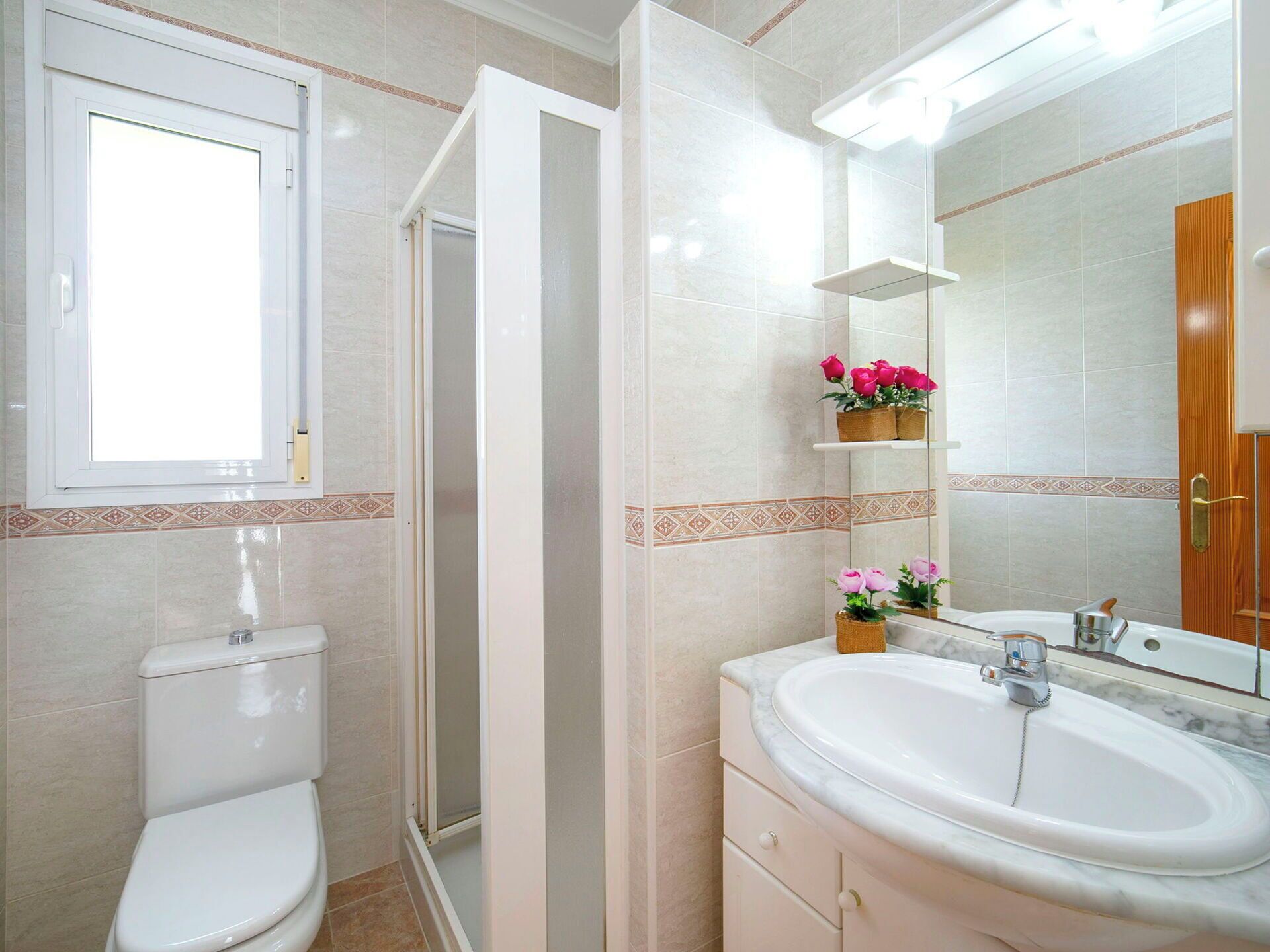 A bathroom with a toilet, a shower, a sink, and a mirror.