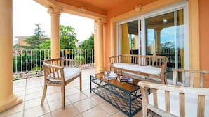 A balcony with two wooden chairs, a small table, and a glass door leading to a garden. - Stunning private villa for 17 people with WIFI, private pool, A/C, TV, patio and pets allowed (Calpe)