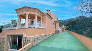 A two-story building with a balcony, stone steps, and a green roof. - Stunning private villa for 17 people with WIFI, private pool, A/C, TV, patio and pets allowed (Calpe)