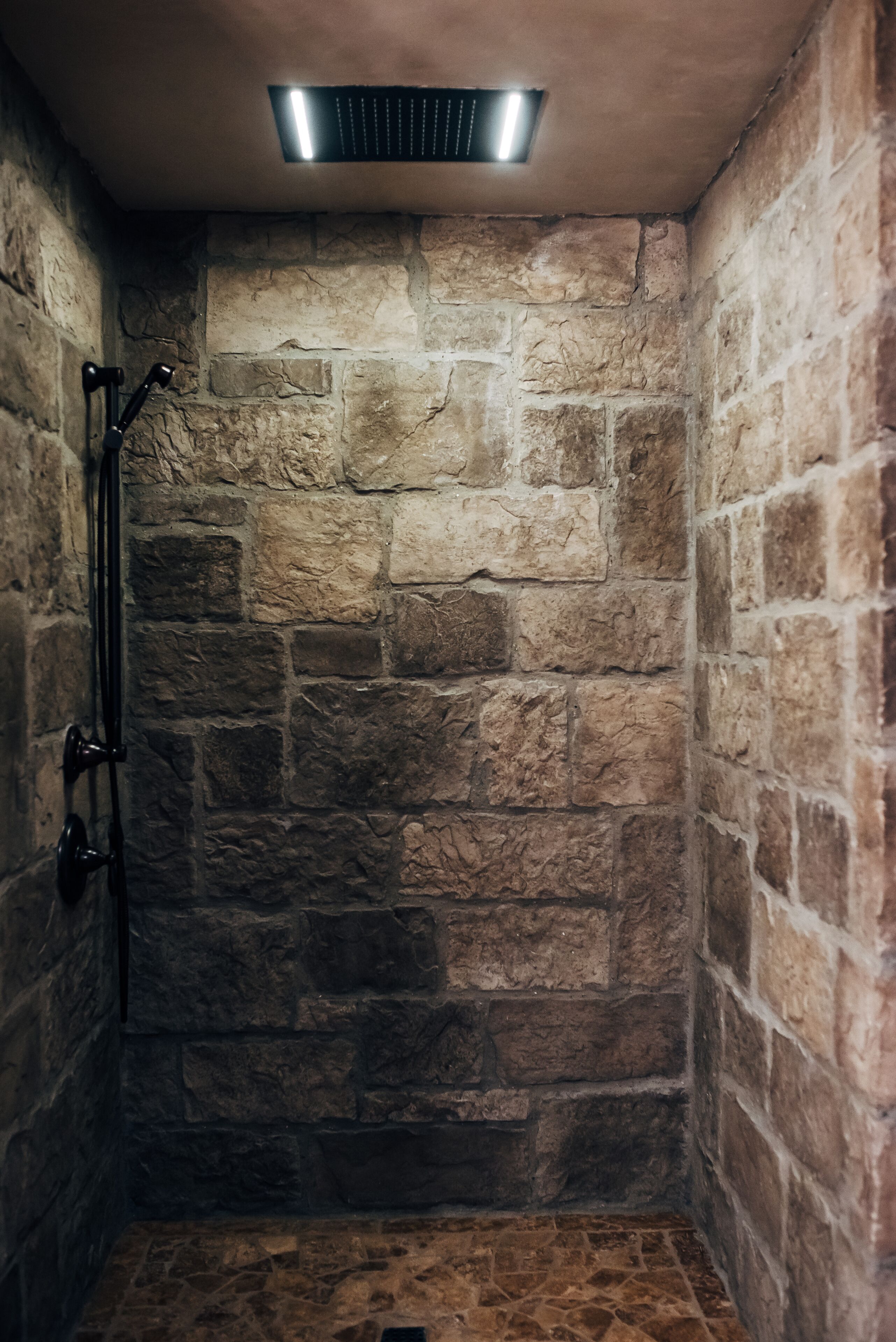 Une douche aux murs en pierre dotée d’un système de ventilation intégré.