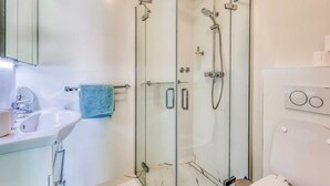 A modern bathroom with a glass-enclosed shower, a white sink, and a toilet. - Apartment Moracea near the beach (Njivice)