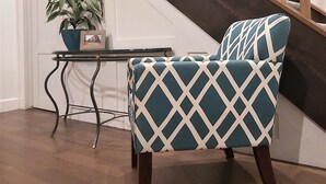 A chair with a diamond pattern, a potted plant, and a staircase.