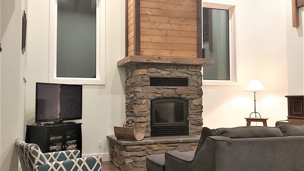 A living room with a stone fireplace, a television, and a sofa.
